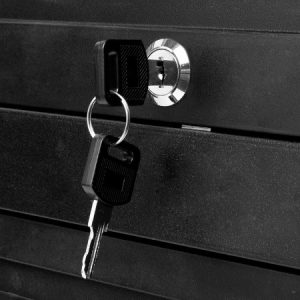Schwarzes Schlüsselpaar steckt in silbernem Schloss eines schwarzen Schränks, symbolisiert Sicherheit und Aufbewahrung.