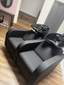 Moderner Friseursalon mit schwarzen Waschstühlen auf Holzfußboden, stilvoll eingerichtet für Haarpflege und Styling.